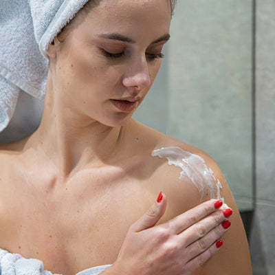 Masser le lait corps sur l'épaule après la douche